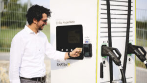 Ein Mann bezahlt kontaktlos mit Kreditkarte an einer Smatrics EnBW Schnellladestation mit Direct Payment Terminal.