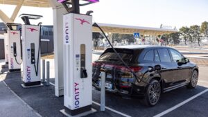 Schwarzer Mercedes EQC lädt an einer IONITY-Schnellladestation mit mehreren Ladepunkten unter Solardach.