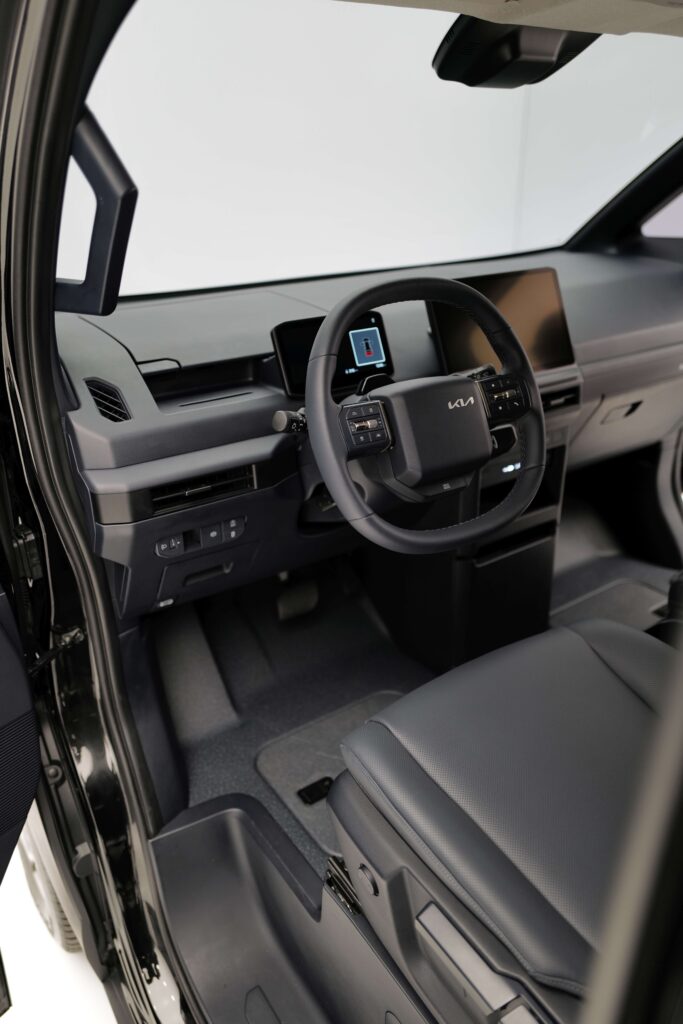 Innenraum des Kia PV5 Cargo mit modernem Lenkrad, großem Touchscreen und digitalem Cockpit.