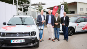 Vier Männer stehen vor zwei Renault E-Autos mit A1-Branding bei der Präsentation des Pilotprojekts in Raasdorf.