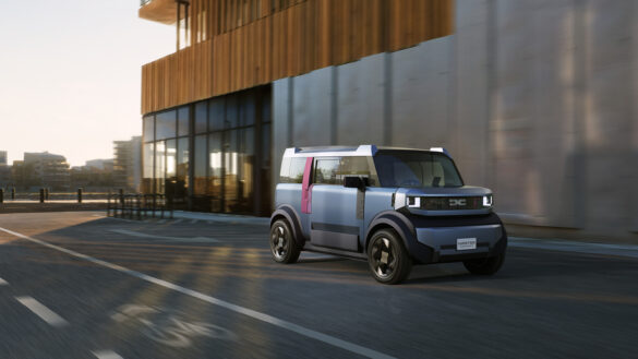 1179_Dacia_Zsub_Shot01_F34_Rolling_OUTPUT_16x9 Dacia Hipster Concept fährt vor einem modernen Gebäude in der Stadt.