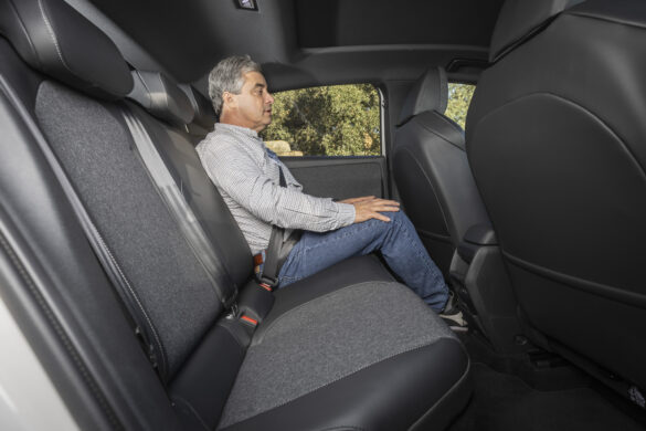 Fondbereich eines kompakten Elektroautos mit großzügiger Beinfreiheit für einen Erwachsenen.