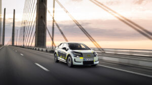 Audi A2 e-tron mit Effizienzbeklebung fährt bei Sonnenuntergang über eine Schrägseilbrücke.